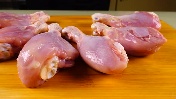 Fresh chicken legs are laid out on a cutting board.