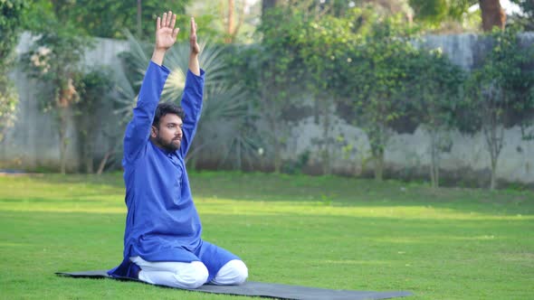 Indian man doing Extended Child Yoga Pose or Prasarita Balasana in an Indian traditional outfit