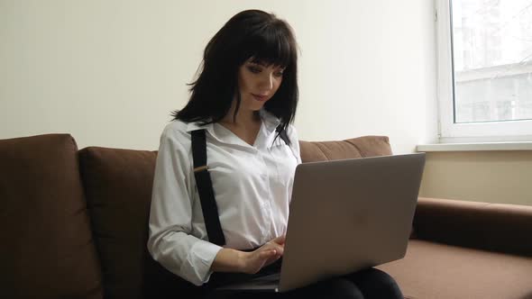 Young Woman Using Laptop at Home Sitting on Sofa