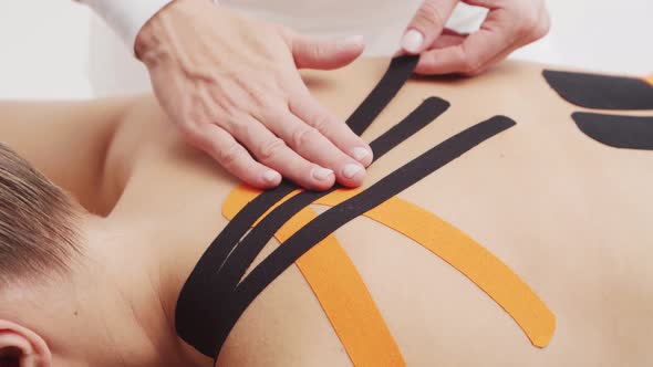 Therapist is applying kinesio tape to female body. Physiotherapy, kinesiology and recovery.