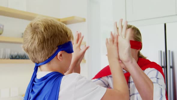 Mother and son in superhero costume giving high five to each other