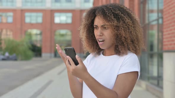 African Woman Reacting to Loss on Smartphone