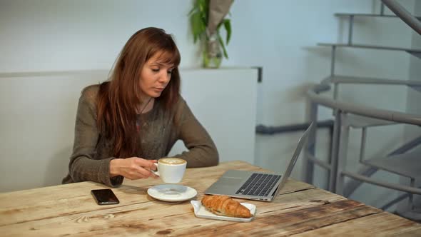 Woman Driking Coffee and Working in Coffeeshop