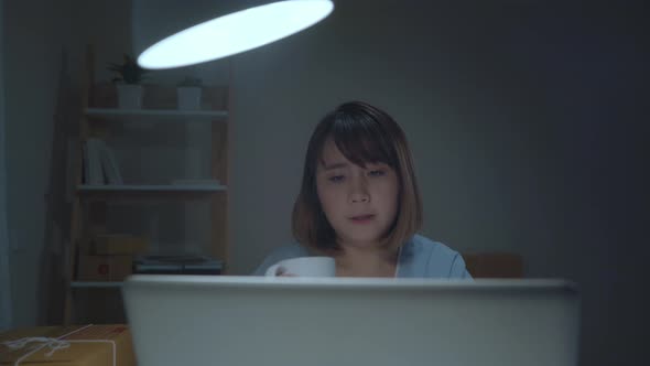 Asian young woman owner of SME online checking product on stock save to computer and drink coffee.