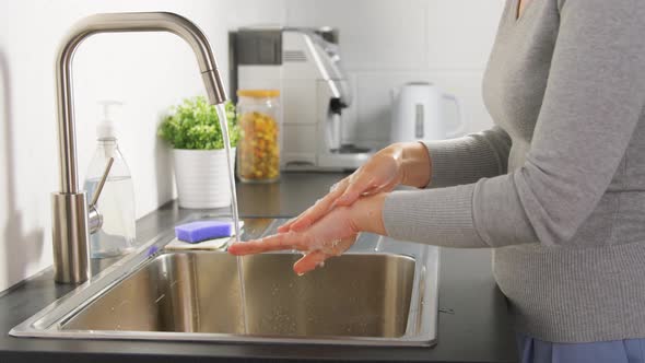 Woman Washing Hands with Liquid Soap in Kitchen