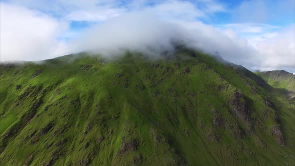 Clouds flying over mountain top, aerial view