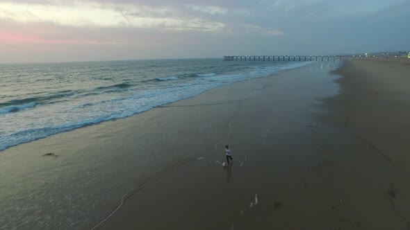 Aerial shot of little boy playing soccer on the beach at sunset.