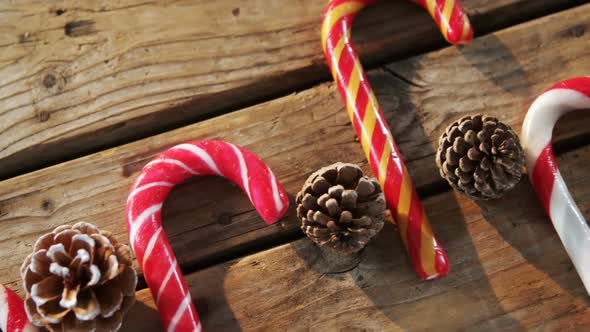 Candy cane with pine cone on wooden table