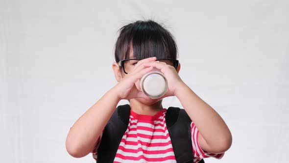 Cute schoolgirl drinking milk from a glass before going to school. Healthy nutrition for children.