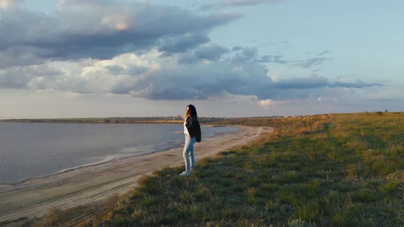 Tracking Aerial Shot of Young Woman Enjoying Sunset in Field Near the Cliff During Beatiful Sunset