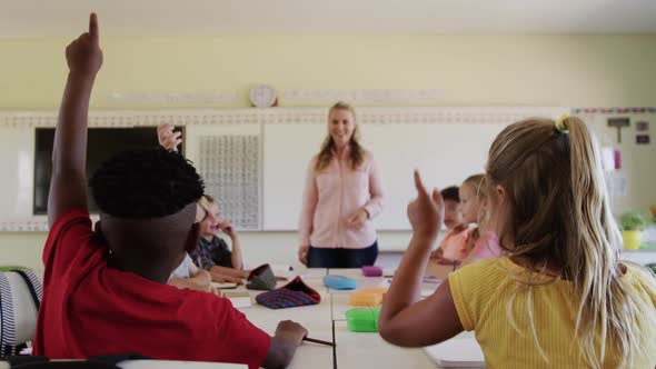 Group of kids raising their hands in the class