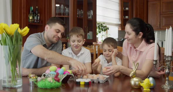 Family Having Fun While Painting and Decorating Eggs for Holiday