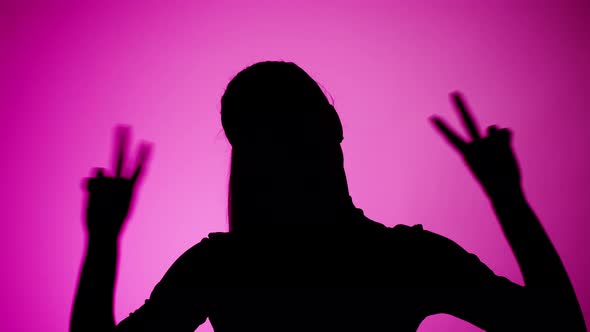 Woman Showing Peace Gesture with Fingers Isolated on Pink Background