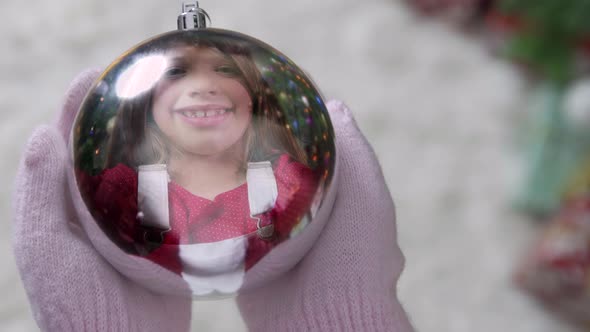 Christmas Festive Holiday winter scene - reflection of cute girl in silver Xmas tree decoration ball