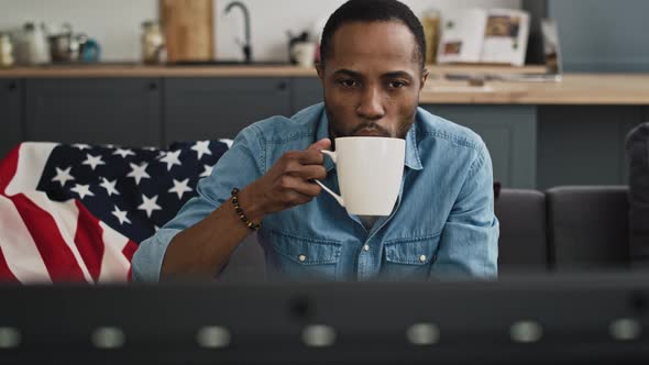 Front view of content black man drinking and watching Tv. Shot with RED helium camera in 8K.