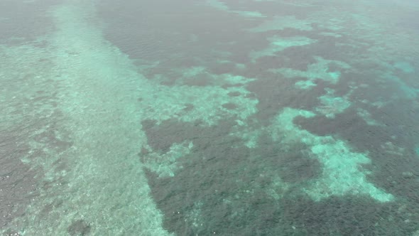 Aerial: Flying over coral reef turquoise water tropical island, scenic travel