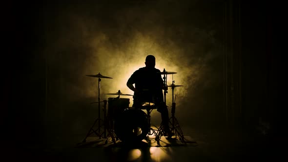 Silhouette Drummer Playing on Drum Kit on Stage in a Dark Studio with Smoke and Neon Lighting