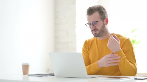 Man Having Wrist Pain While Using Laptop in Office