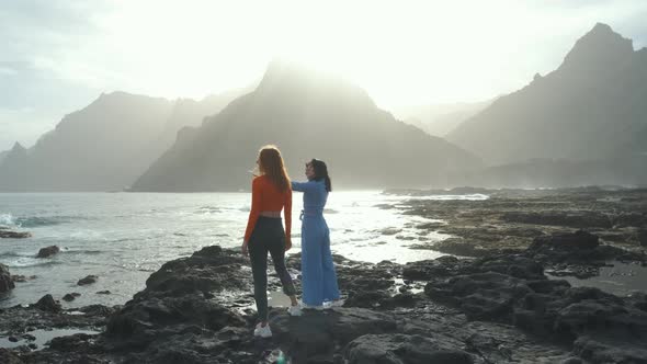 Two Beautiful Girlfriends Walk Along the Volcanic Beach in the North of the Canary Island of