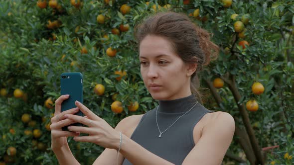 Woman Taking Selfie Picture in an Orange Orchard