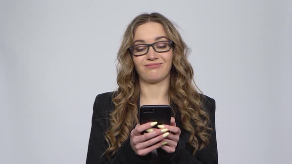 Angry Businesswoman Texting on Her Phone on Gray Background in Studio