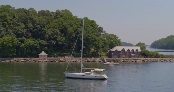 Panning Around a Sail Boat Anchored on a Harbor Near a Forest