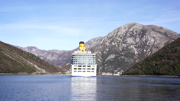 Luxury Cruise Ship Sails Along the Bay Past the Mountainous Coastline