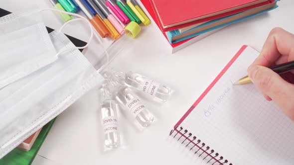 Medical workplace with ampoules of coronavirus vaccine, books and face masks