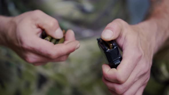 Close Up Shot of Hands Loading a Magazine Clip with Bullets Man Hands in Camouflage Clothes