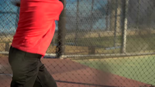 A boy swings the bat and practices little league baseball at the batting cages.