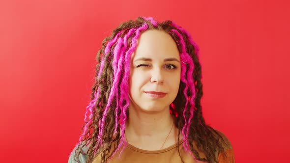 Young Beautiful Woman with Curly Hairstyle Smiling and Winking on Red Background