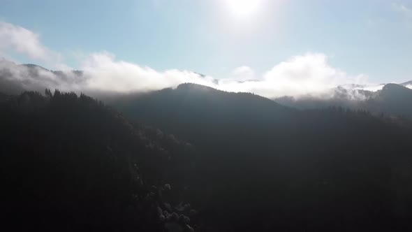 Aerial View of Dawn Over the Mountains. Flying Through the Clouds. Sunrise