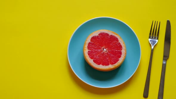 Bright Fresh Grapefruit on Color Plate on Yellow Background