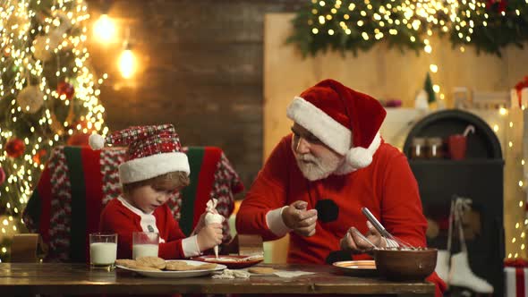 Santa Claus with Child Helper Baking Christmas Cookies and Prepare Xmas or New Year.