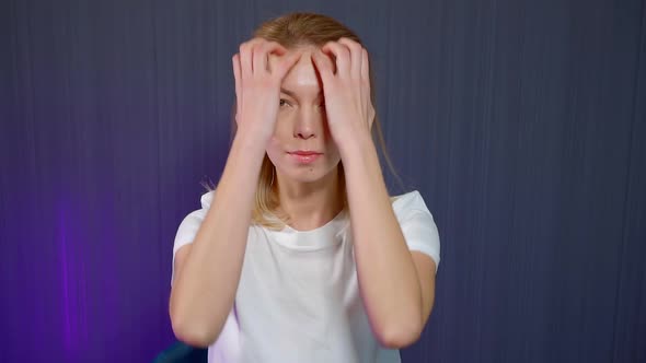 Close-up Portrait of a Blonde Girl Who Is in the Studio on a Blue Background, She Is Doing Head