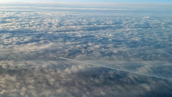 Incredible view from the cockpit of an airplane flying high above the clouds leaving a long white co