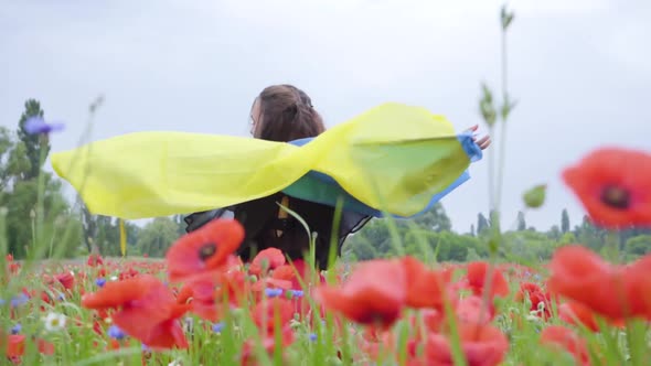 Portrait Adorable Young Woman Dancing in a Poppy Field Holding Flag of Ukraine in Hands Outdoors