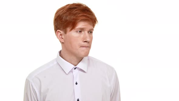 Confused Young Man with Red Hair Standing on White Background Unsure