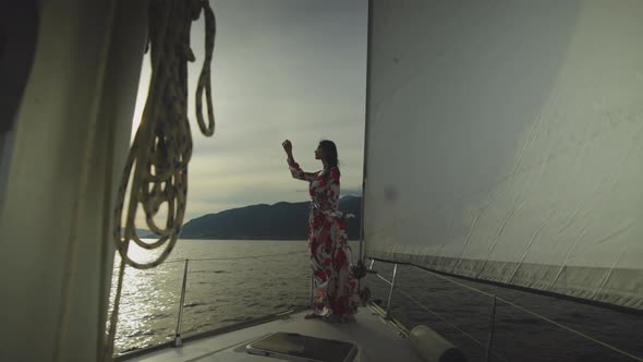 Brunette in dress standing on yacht bow