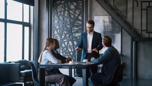 Meeting in the loft: young businessman discussing with him business team