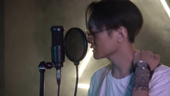 Young Modern Asian Man in a Recording Studio Singing Into a Microphone