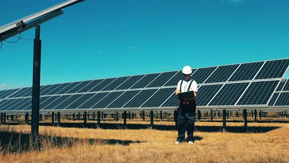 Male Specialist Is Observing a Solar Power Field. Energy Saving, Energy Efficiency, Renewable Energy