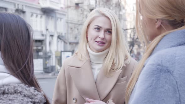 Portrait of Happy Young Blond Woman Talking with Friends on the Street. Cheerful Caucasian Girls