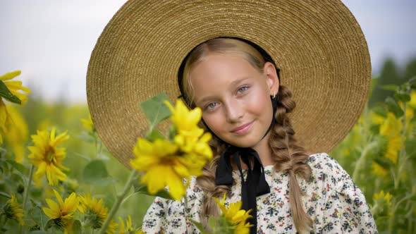 Portrait Beautiful Girl with Two Braids in Hat on Sunflowers Field in Summer Village. Pretty Rustic