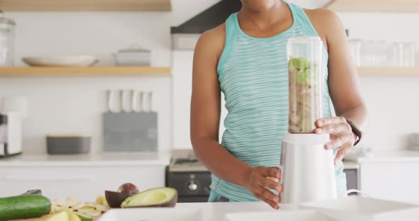 Happy african american woman preparing healthy drink in kitchen