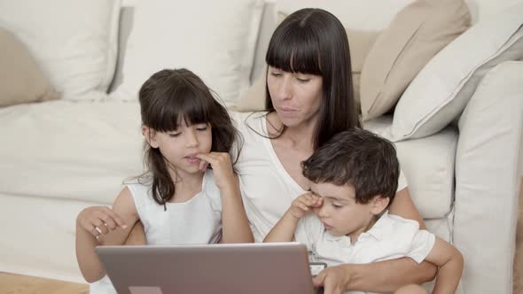 Mom and Two Kids Using Learning App on Laptop