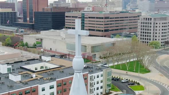 Aerial view around a church cross, with city street background - circling, drone shot