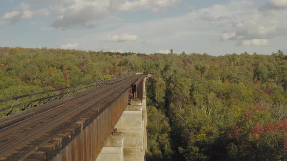 Flying beside a rusty railroad trestle during an early fall golden hour AERIAL