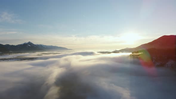 Drone shot  of an incredible landscape covered under the fog with surrounding mountains in the morni