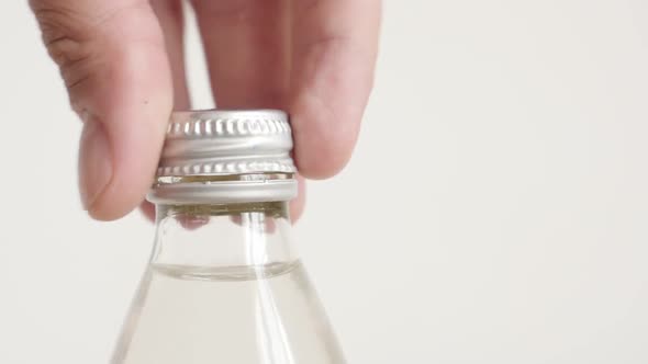 Metal cap unscrewed from glass bottle slow motion video